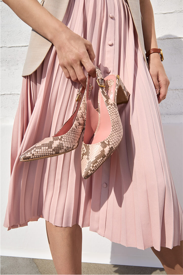 person holding high heel shoes for spring workwear outfit