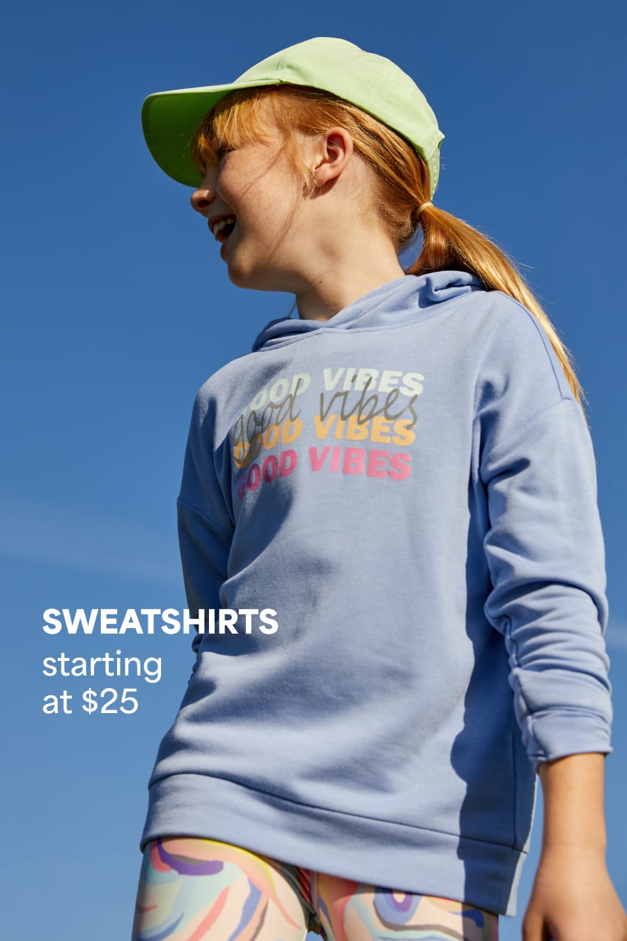 Model wearing Stitch Fix kids clothes including mint hat and sweatshirt saying “good vibes.” Text reads: SWEATSHIRTS starting at $25.