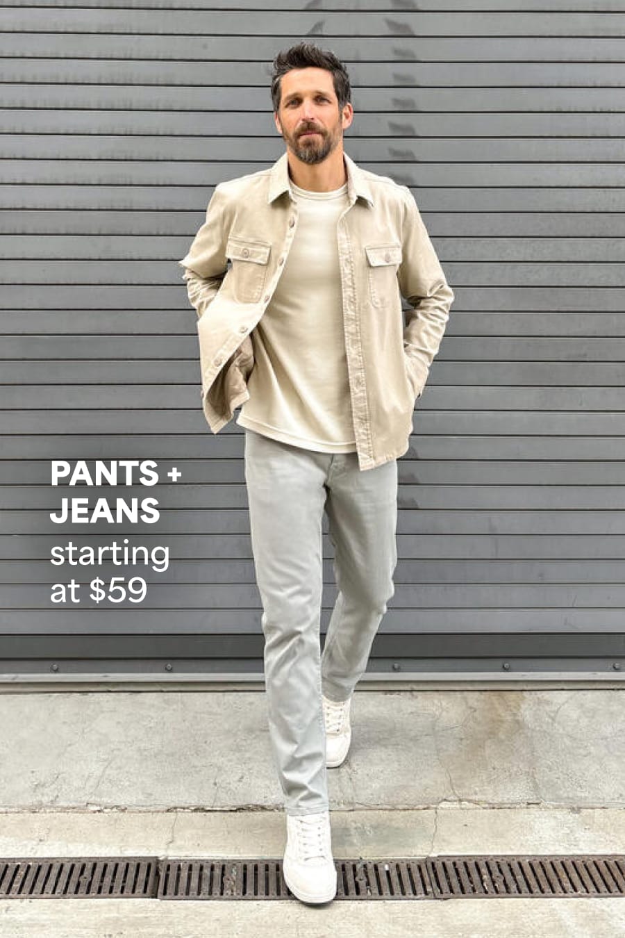 Model wearing Stitch Fix men’s clothes including beige shirt jacket, cream tee, gray denim jeans and white sneakers. Text reads: Pants+Jeans starting at $59