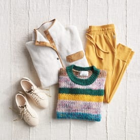 Athleisure clothing including a striped sweater, white and tan fleece jacket, yellow jogger pants and white sneakers.